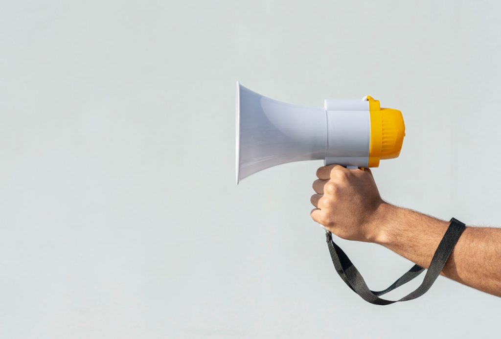 Męska dłoń trzymająca megafon