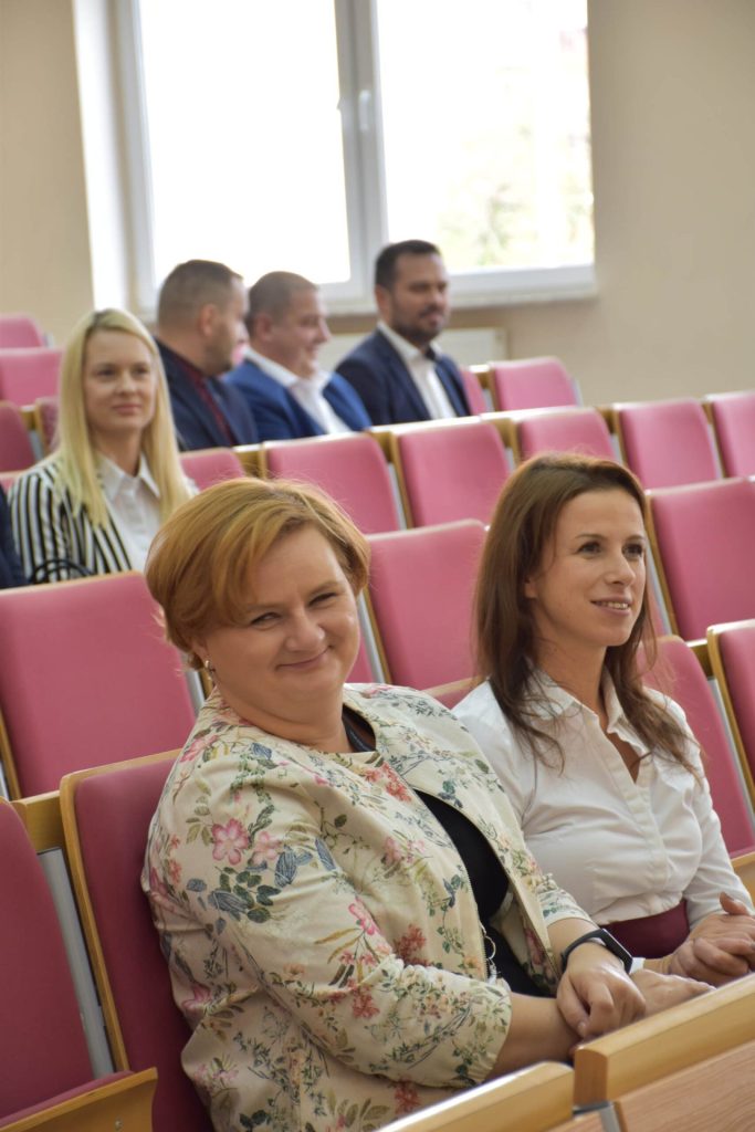 Dwie uśmiechnięte uczestniczki uroczystości nagród siedzą obok siebie w auli.