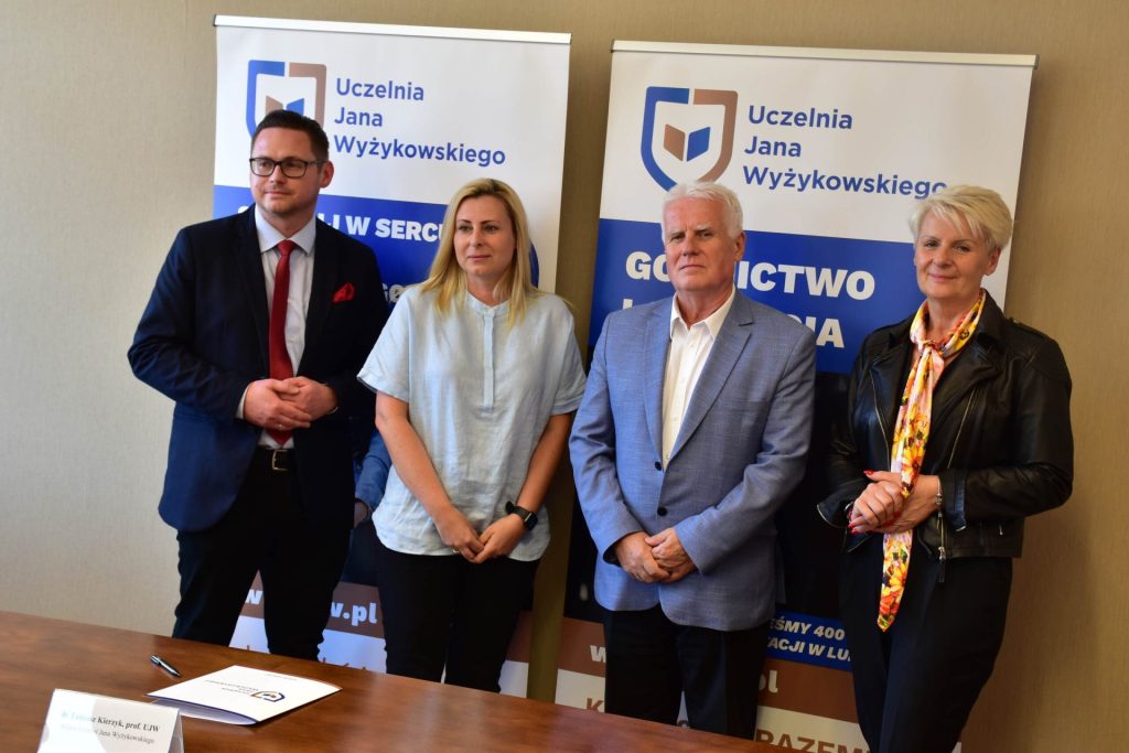 The four participants in the signing of the agreement with the school pose at the table.