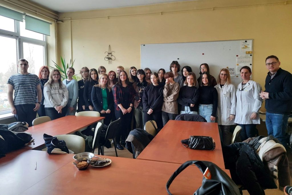 grupa kilkudziesięciu młodych osób osób pozuje do grupowego zdjęcia w sali szkoleniowej