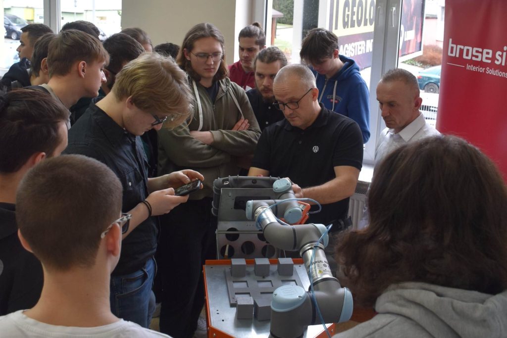 Duża grupa mężczyzn stoi wokół robota przemysłowego