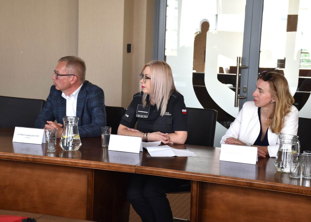 Uczestnicy spotkania partnerskiego, w tym funkcjonariuszka, siedzą przy stole konferencyjnym.