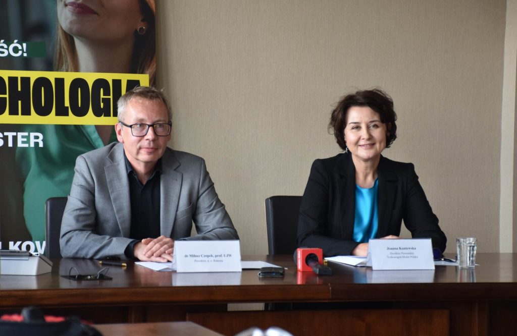 Kobieta i mężczyzna siedzą przy stole prezydialnym