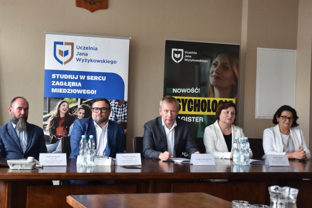 3 mężczyzn i 2 kobiety siedzą przy stole prezydilanym