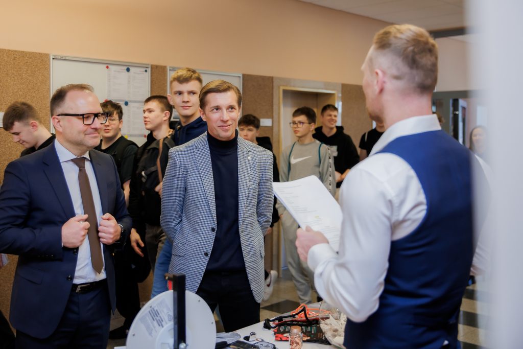 Prowadzący prezentuje materiały osobom zgromadzonym przy stoisku podczas Dnia Drzwi Otwartych.