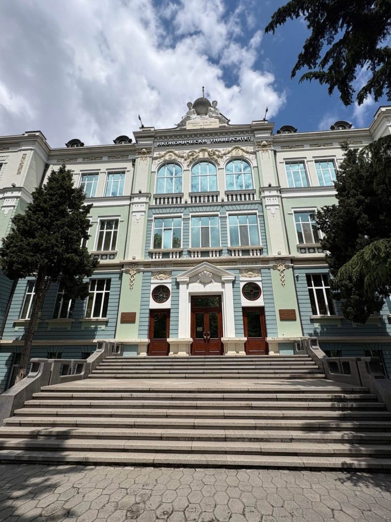 Reprezentacyjna fasada uczelni z szerokimi schodami prowadzącymi do wejścia.