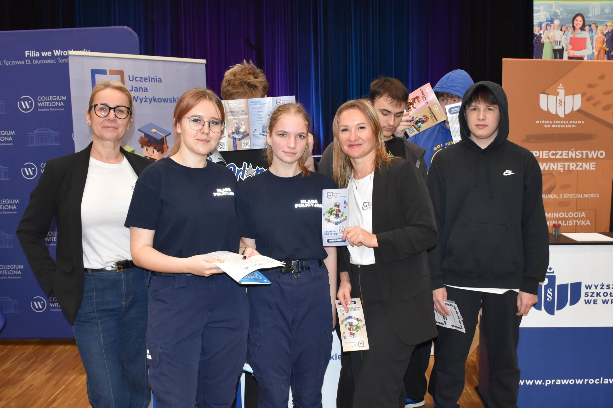 Grupa 8 osób stoi z ulotkami uczelni