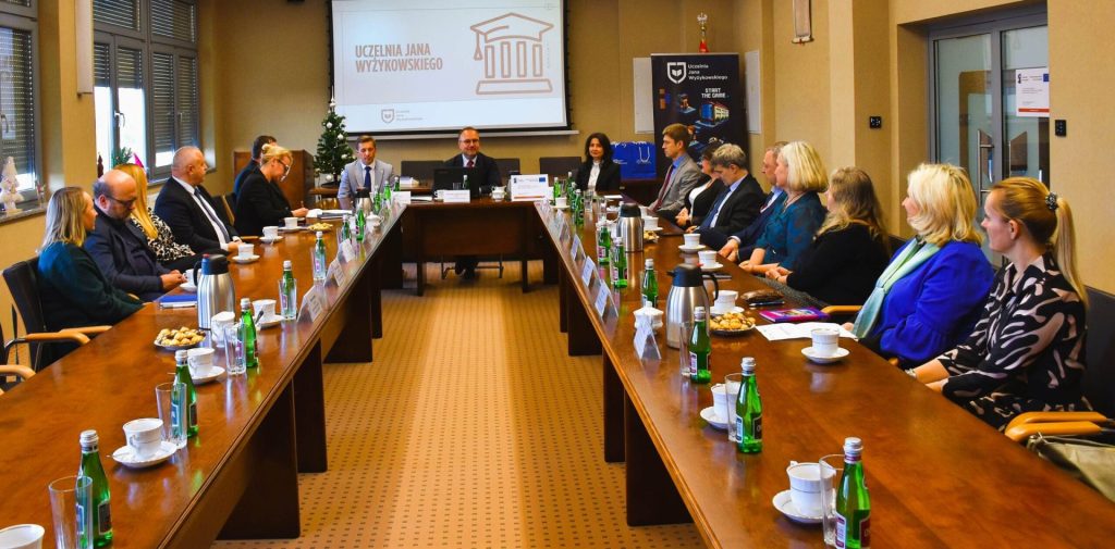 Uczestnicy posiedzenia Rady Dyrektorów UJW siedzą przy stołach ustawionych w podkowę.