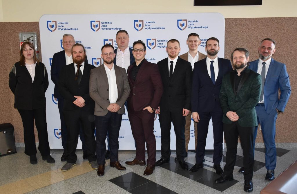 Uczestnicy obron na kierunkach inżynierskich pozują na tle ścianki z logo UJW.