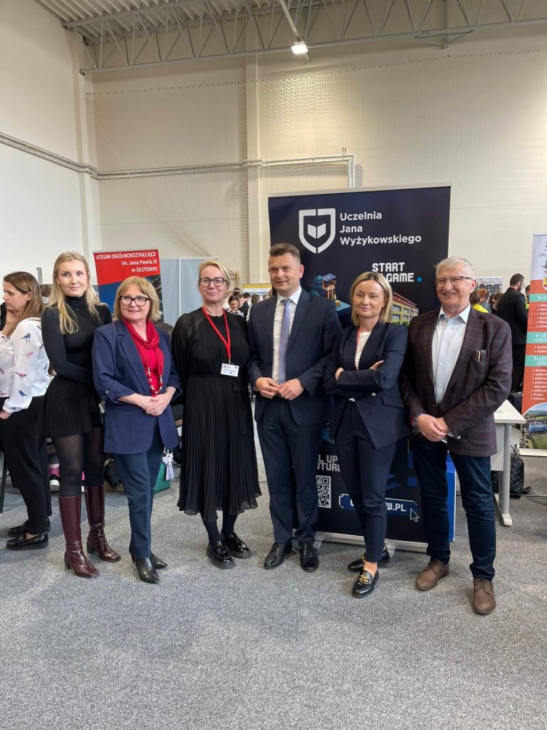 Przedstawiciele instytucji pozują przy stoisku UJW na targach edukacyjnych.