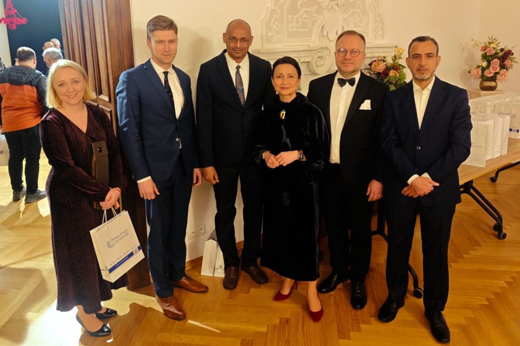 Sześcioro uczestników uroczystości pozuje w eleganckiej sali.