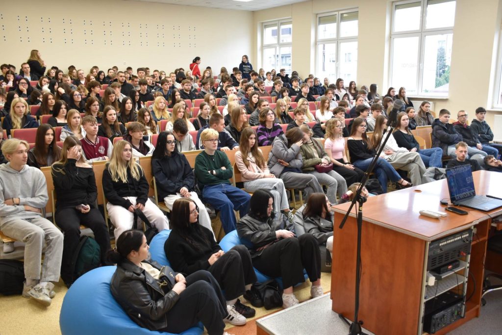 Publiczność wypełnia salę wykładową uczelni.