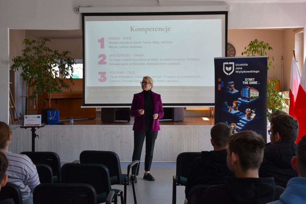 Prelegentka omawia kompetencje przy ekranie prezentacji.