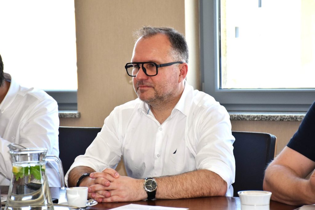 Mężczyzna w białej koszuli i okularach przy stole podczas spotkania z KGHM INOVA.