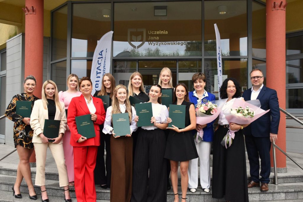 Grupa po obronach prac dyplomowych przed wejściem do UJW, z dyplomami i kwiatami.