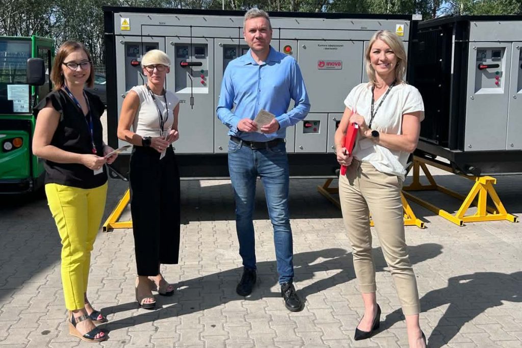 Cztery osoby pozują przy urządzeniach technicznych podczas wizyty w INOVA.