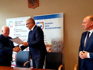 Uścisk dłoni podczas przekazania dokumentów współpracy UJW i samorządu województwa.