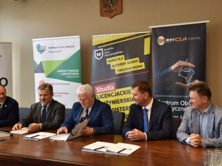 Przedstawiciele UJW, CBJ i Mercus Logistyka podpisują dokumenty przy wspólnym stole.
