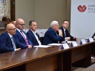 Uczestnik spotkania klastra energetycznego przemawia do mikrofonu przy stole.