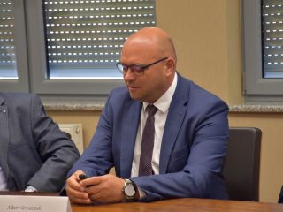 Mężczyzna w niebieskim garniturze zabiera głos podczas spotkania klastra energetycznego.