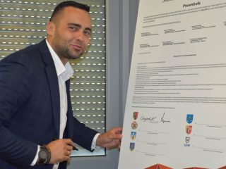 Mężczyzna w granatowej marynarce z markerem przy dokumencie klastra energetycznego.