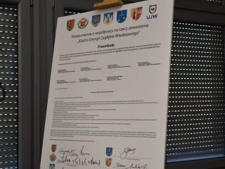 Podpisane porozumienie klastra energetycznego na sztaludze przy oknie.