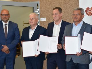 Przedstawiciele partnerów klastra prezentują podpisane dokumenty na wspólnym zdjęciu.