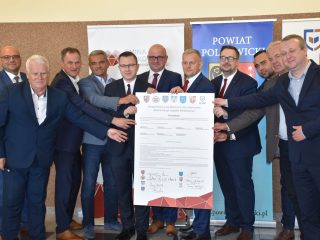 Przedstawiciele partnerów klastra energetycznego pozują z dużym dokumentem porozumienia.