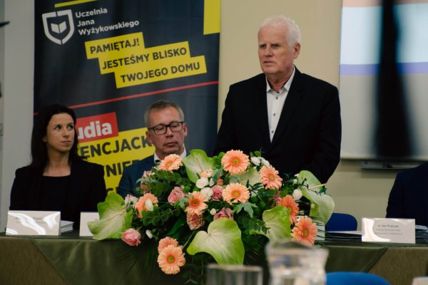 Rektor uczelni przemawia za stołem prezydialnym