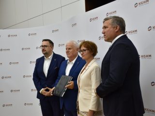 Czworo przedstawicieli pozuje z dokumentami na tle logo KGHM.
