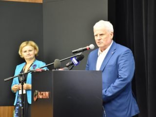 Mężczyzna w niebieskim garniturze przemawia przy mównicy KGHM.