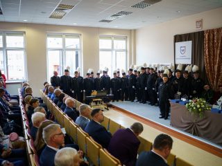 Widok auli podczas inauguracji, z chórem górniczym przed stołem prezydialnym i publicznością w rzędach.