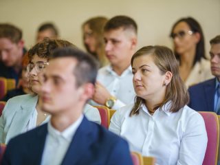 Studenci siedzą w rzędach foteli podczas inauguracji roku akademickiego.