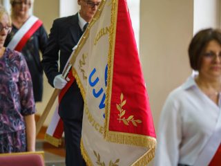 Poczet sztandarowy z biało-czerwonymi szarfami wnosi sztandar UJW do auli.