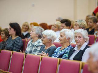 Uczestniczki inauguracji PUTW siedzą w auli, część z nich klaszcze.