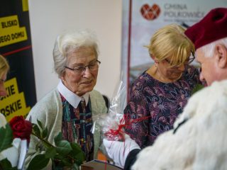 Rektor wręcza upominek uczestniczce w okularach i jasnym kardiganie podczas inauguracji PUTW.