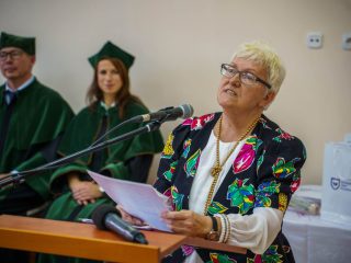 Kobieta w kwiecistej bluzce odczytuje tekst przy mównicy podczas inauguracji PUTW.