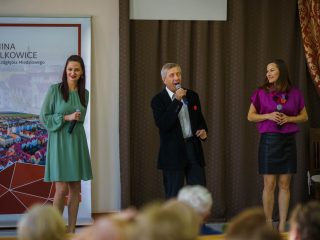 Mężczyzna śpiewa do mikrofonu między dwiema wokalistkami podczas inauguracji PUTW.