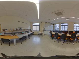 Panorama pracowni technicznej z aparaturą, komputerami i stanowiskami laboratoryjnymi.