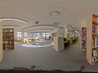Panorama wnętrza biblioteki z regałami i stanowiskami czytelniczymi.