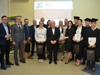 Grupa wyróżnionych uczestników i przedstawicieli uczelni pozuje z dyplomami i upominkami.