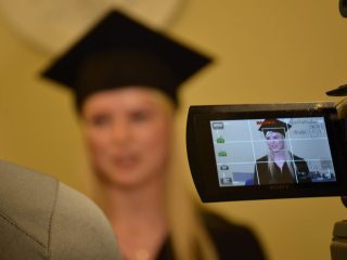 Ekran kamery pokazuje nagrywaną absolwentkę w birecie.