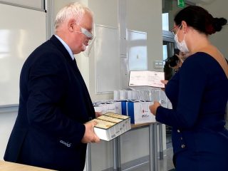 Mężczyzna trzyma książki podczas wręczania nagrody kobiecie w granatowej sukience.