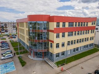 Budynek UJW w Polkowicach z przeszklonym narożnikiem, parkingiem i wejściem.