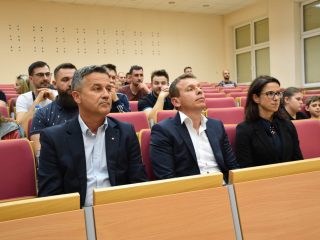 Dwaj mężczyźni i kobieta siedzą w pierwszym rzędzie, słuchając wykładu o ratownictwie.