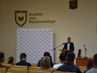 Uczestnicy wykładu o ratownictwie słuchają mężczyzny stojącego przy mównicy.