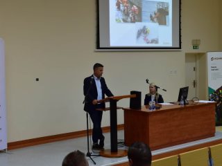 Mężczyzna prowadzi prezentację przy ekranie; na widowni siedzą uczestnicy w koszulkach z napisem Ratownik.