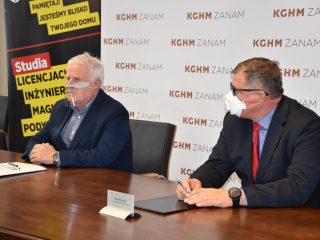 Sygnatariusze siedzą przy stole na tle logo KGHM ZANAM.