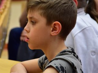 Chłopiec siedzi przy pulpicie w auli i przygląda się prezentacji.