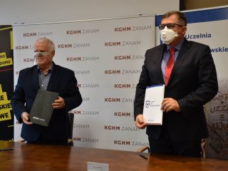 Przedstawiciele UJW i KGHM ZANAM prezentują teczki z podpisaną umową.